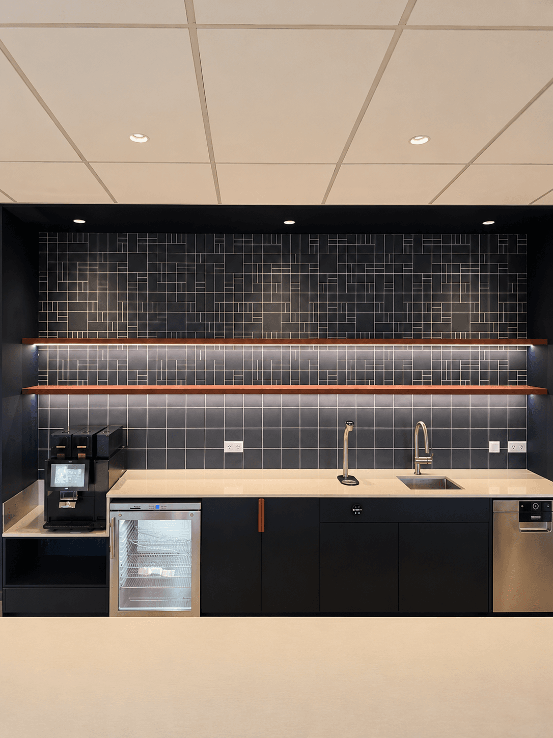 A coffee bar with a charcoal grid-tile backsplash in a linear pattern, black cabinets, and floating wood shelves.